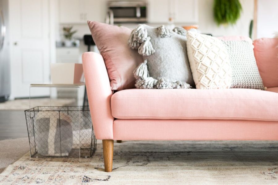 Różowa sofa retro z drewnianymi nóżkami.
